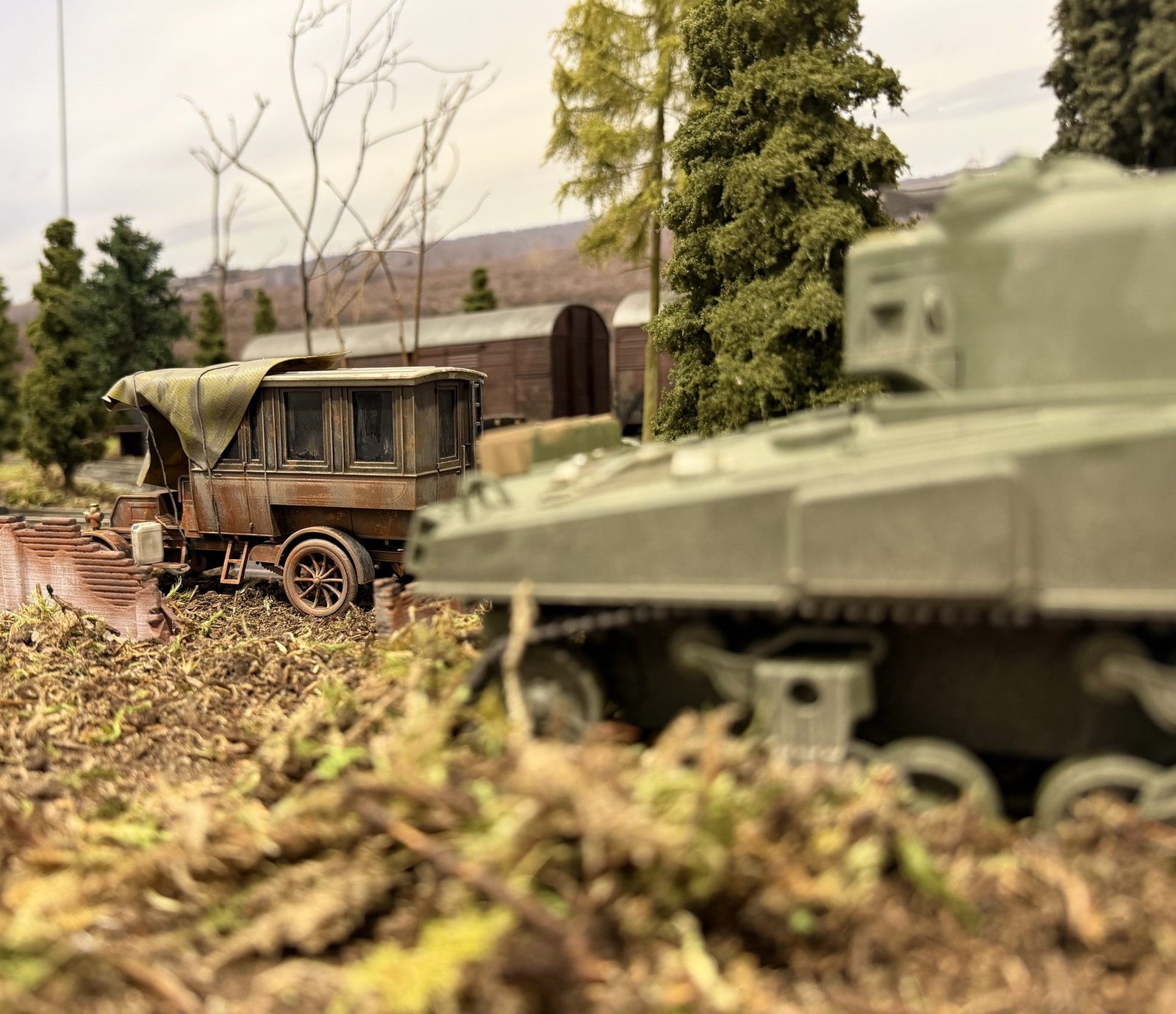 Rusty car and Sherman tank on a model railway layout
